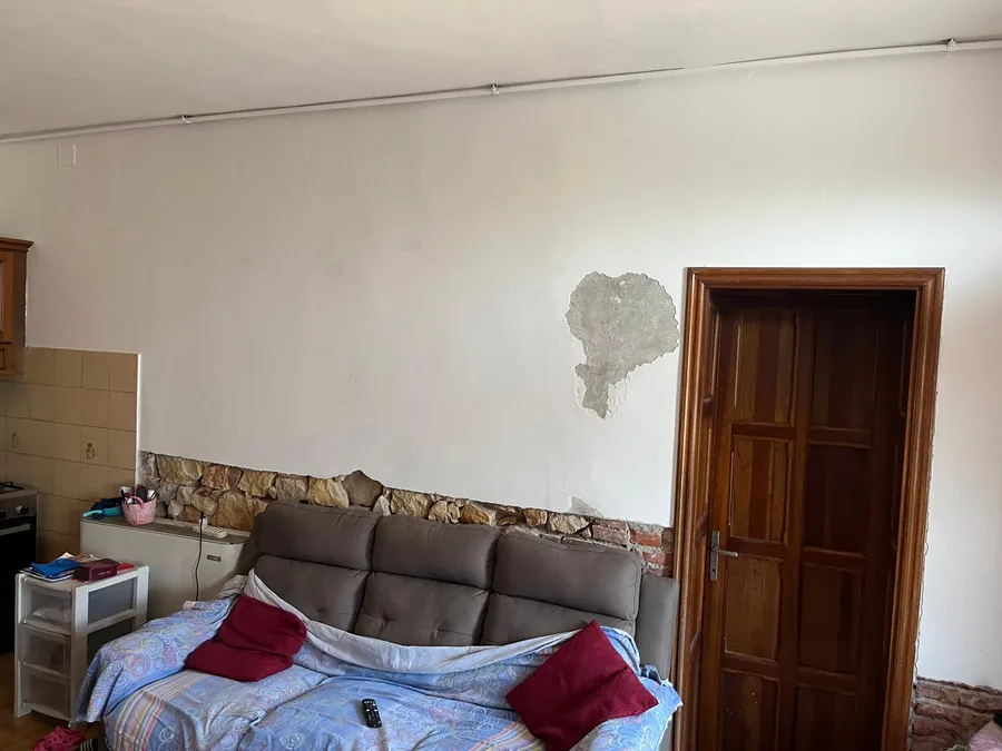 Decorazione pietra spaccata a 3 colori, prima: parete bianca con macchia di umidità